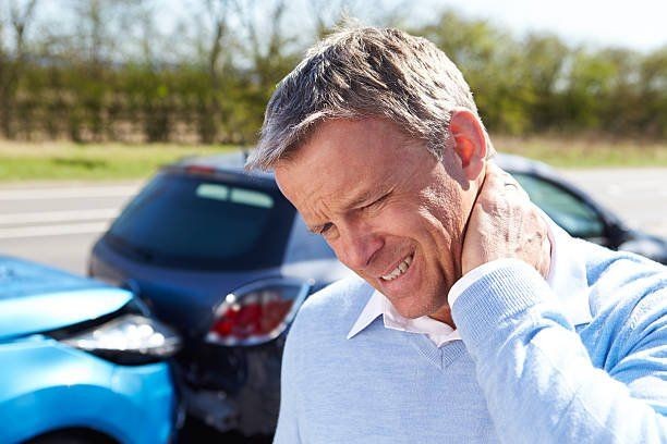 Man holding his neck in pain near two cars involved in a rear-end collision on the road.